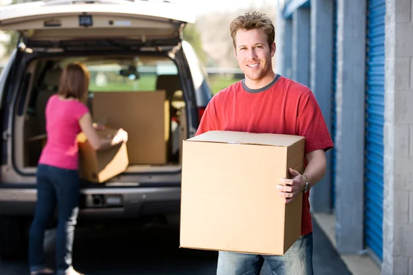 Opslag: Man met doos met vrouw achter Stockafbeelding