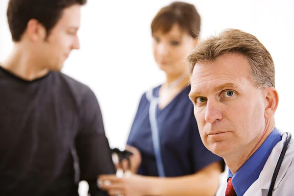 Doctors: Serious Doctor with Patent and Nurse — Stock Photo, Image