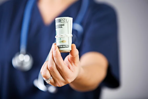 Sairaanhoitaja: ojentamassa rullaa dollareita — kuvapankkivalokuva