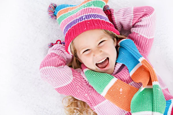 Inverno: Rindo menina deitada na neve — Fotografia de Stock