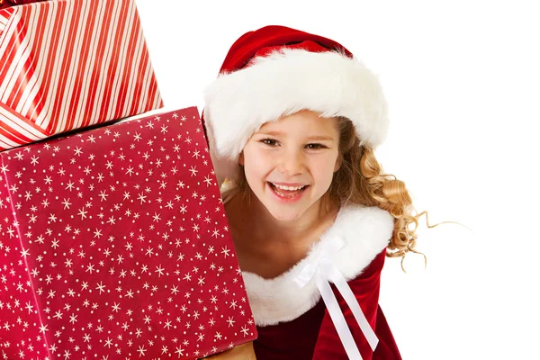 Natal: Pequena menina espreita por trás dos presentes — Fotografia de Stock