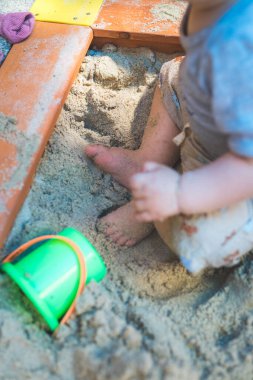 Toddler baby playing concept: Cut out of young boy playing in the sandbox, summer time