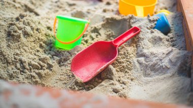 Çocuklar kum havuzunda plastik oyuncaklar. Kürek, seçici odaklanma.