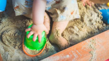 Bebek oyunu konsepti: Genç çocuk kum havuzunda oynuyor, yaz zamanı