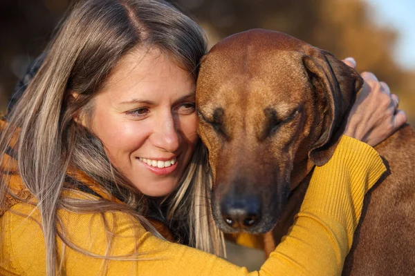 少女とローデシアのリッジバックの肖像画 犬は目を閉じた 黄色の背景 ストック写真