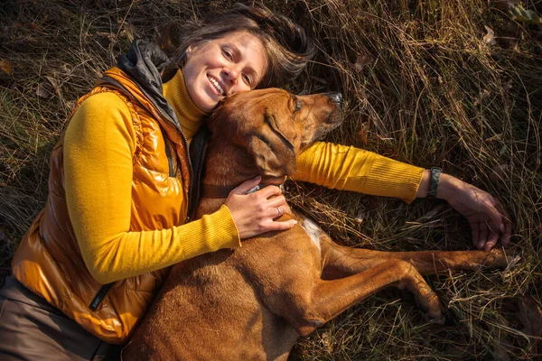 Flicka Gul Tröja Och Rhodesian Ridgeback Ligger Tillsammans Höstgräset Royaltyfria Stockbilder