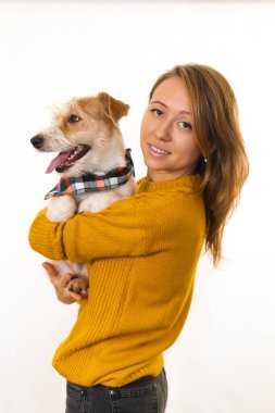 Sarı ceketli bir kız bandana atkılı Jack Russell Terrier köpeği tutuyor. Beyaz arkaplanda izole et.