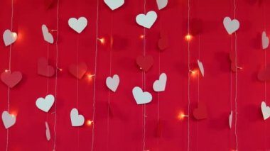 Kırmızı arka plan, beyaz kalpler ve yanıp sönen çelenk lambaları. Kamera hareketi. Sevgililer Günü konsepti
