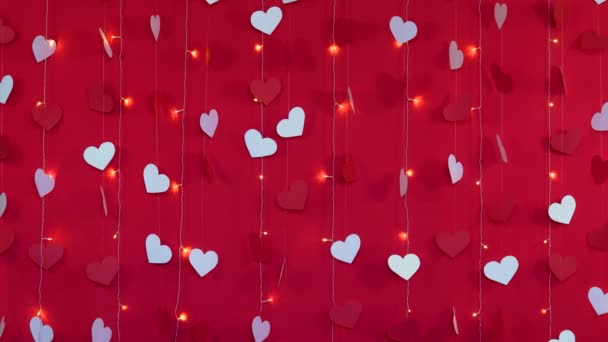 Červené pozadí s bílými srdci a blikající věnec lampy. Valentines day concept — Stock video