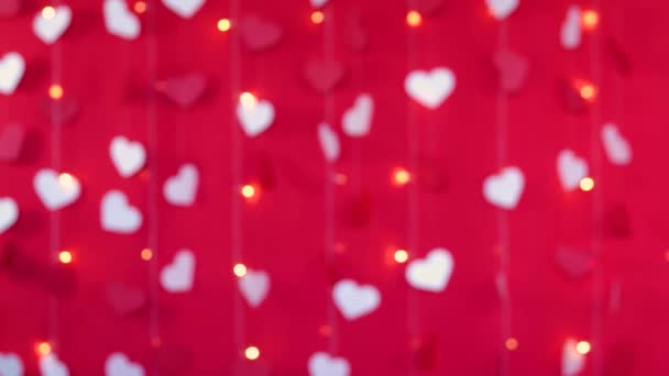Röd bakgrund med vita hjärtan och blinkande girlanslampor ur fokus. Alla hjärtans dag koncept — Stockvideo