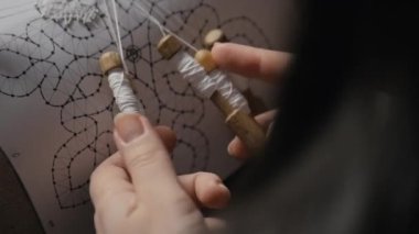 Female hands weaving lace with bobbins