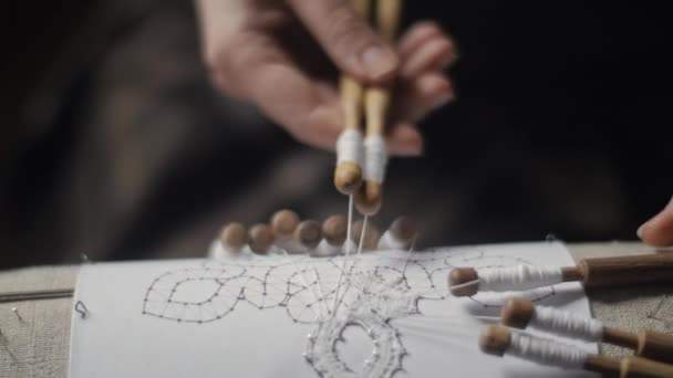 Primer plano de las manos femeninas tejiendo encaje con bobinas — Vídeo de stock