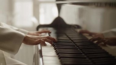 Beyaz takım elbiseli bir kadın piyano çalıyor.
