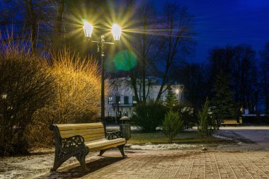 İlk karla kaplanmış eski ahşap bank sokak lambasıyla aydınlatılır. Akşamları şehir parkı