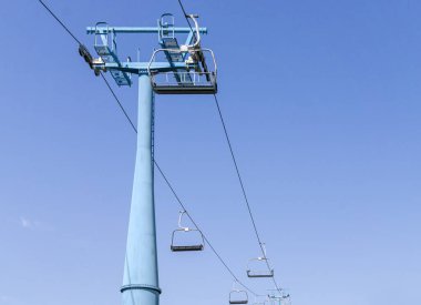 Pillar and empty chairs of ski lift against blue sky. Cable way of ski resort. Copy space