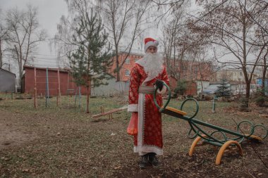 Noel Baba gibi giyinmiş, çantasında mandalinalar olan üzgün bir adam oyun parkında duruyor. Kışın kar olmayınca ısınma sorunu..