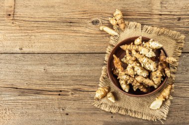 Tahta arka plandaki bir kasede çiğ Kudüs enginarı. Taze kazılmış yumru pişirmeye hazır, geleneksel yararlı yiyecekler, üst manzara.