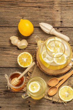 Tahta arka planda cam bir fincanda limonlu ve ballı sıcak zencefil çayı. Alternatif tıp, soğuk algınlığı ve grip için doğal ev tedavisi.