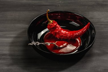 Olgun acı biber sosu ve siyah ahşap arka planda bütün sebzeler. Farklı yemekler için geleneksel malzeme, mutfak arkaplanı, kopyalama alanı