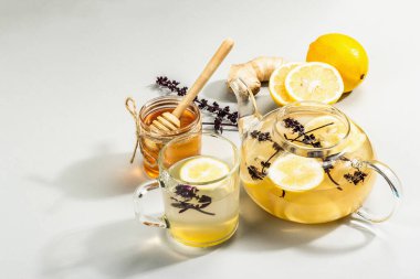 Açık gri arka planda cam bir fincanda limonlu ve ballı sıcak zencefil çayı. Alternatif tıp, soğuk algınlığı ve grip için doğal ev tedavisi, modern sert ışık, karanlık gölge, kopyalama alanı