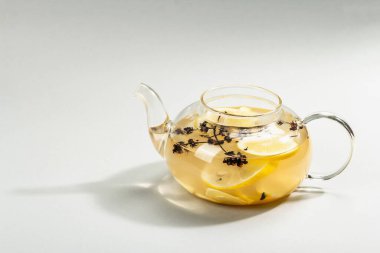 Açık gri arka planda cam bir fincanda limonlu ve ballı sıcak zencefil çayı. Alternatif tıp, soğuk algınlığı ve grip için doğal ev tedavisi, modern sert ışık, karanlık gölge, kopyalama alanı