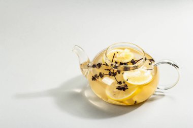 Açık gri arka planda cam bir fincanda limonlu ve ballı sıcak zencefil çayı. Alternatif tıp, soğuk algınlığı ve grip için doğal ev tedavisi, modern sert ışık, karanlık gölge, kopyalama alanı