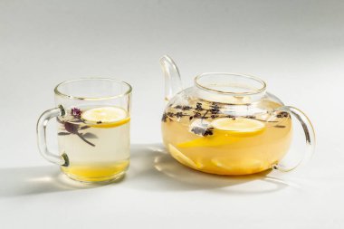 Açık gri arka planda cam bir fincanda limonlu ve ballı sıcak zencefil çayı. Alternatif tıp, soğuk algınlığı ve grip için doğal ev tedavisi, modern sert ışık, karanlık gölge, yakın çekim