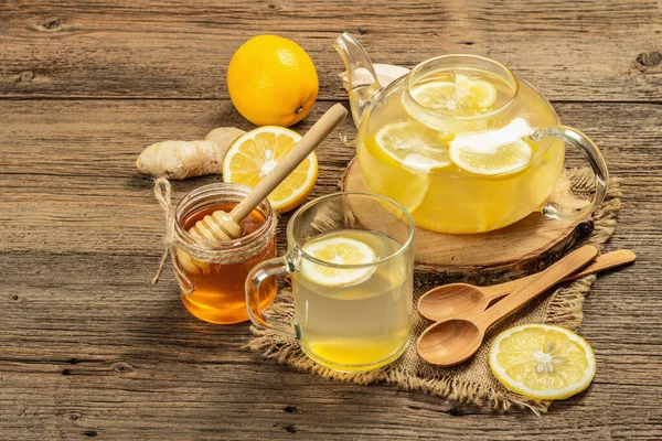 Tahta arka planda cam bir fincanda limonlu ve ballı sıcak zencefil çayı. Alternatif tıp, soğuk algınlığı ve grip için doğal ev tedavisi, kopyalama alanı