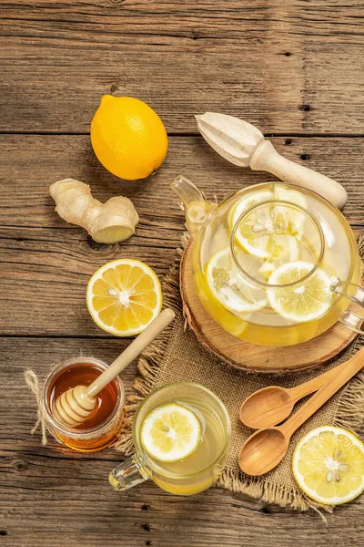 Tahta arka planda cam bir fincanda limonlu ve ballı sıcak zencefil çayı. Alternatif tıp, soğuk algınlığı ve grip için doğal ev tedavisi.