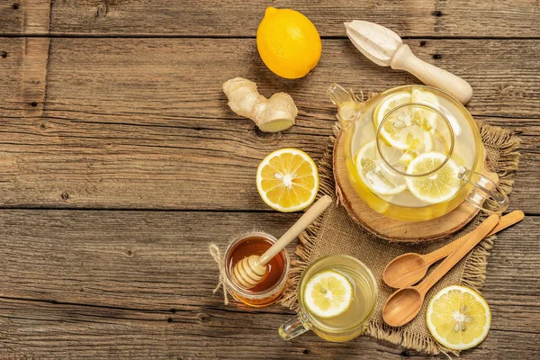 Tahta arka planda cam bir fincanda limonlu ve ballı sıcak zencefil çayı. Alternatif tıp, soğuk algınlığı ve grip için doğal ev tedavisi.