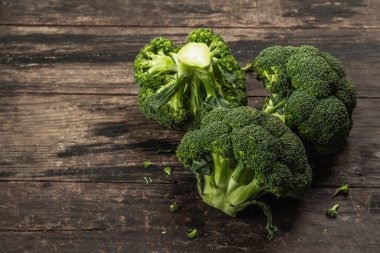 Eski ahşap arka planda yeşil taze brokoli. Diyet için olgun sebzeler, sağlıklı yiyecekler, organik yiyecekler. Düz konum, makro fotoğraf, seçici odak, kopyalama alanı
