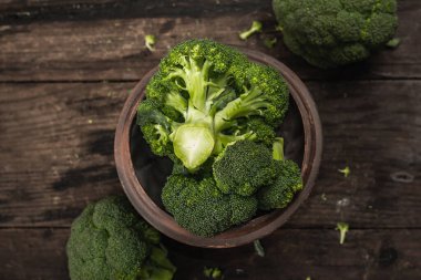 Eski ahşap arka planda yeşil taze brokoli. Diyet için olgun sebzeler, sağlıklı yiyecekler, organik yiyecekler. Düz yatış, makro fotoğraf, seçici odak, üst görünüm