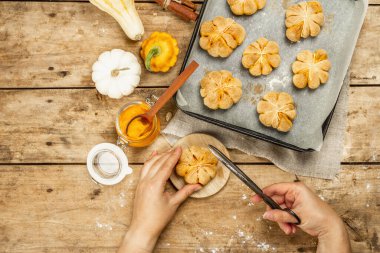 Balkabağı çörekleri ya da bisküviler, geleneksel sonbahar pişmiş ürünler. Kadın eli kurabiyeleri tutar. Mevsimlik ev yapımı yemekler ve sonbahar dekorasyonu. Eski tahta arka plan, üst görünüm