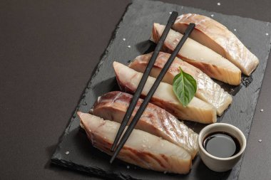 Çiğ pollock (Pollachius virens) parçaları. Sağlıklı yaşam tarzı için taze balık. Deniz tuzu, yeşillik, soya sosu, yemek çubukları. Siyah taş arkaplan, boşluğu kopyala