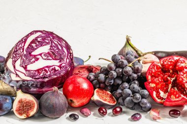 Mavi, kırmızı ve mor yiyecek. Meyve ve sebzelerin aşçılık geçmişi. Taze incir, erik, soğan, patlıcan, üzüm, lahana, elma, sarımsak, köpek ağacı, nar. Beyaz arkaplan, modaya uygun sert ışık