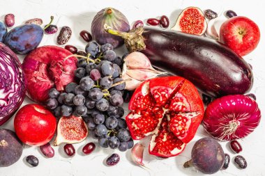 Mavi, kırmızı ve mor yiyecek. Meyve ve sebzelerin aşçılık geçmişi. Taze incir, erik, soğan, patlıcan, üzüm, lahana, elma, sarımsak, köpek ağacı, nar. Beyaz arkaplan, modaya uygun sert ışık