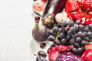 Mavi, kırmızı ve mor yiyecek. Meyve ve sebzelerin aşçılık geçmişi. Taze incir, erik, soğan, patlıcan, üzüm, lahana, elma, sarımsak, köpek ağacı, nar. Beyaz arkaplan, modaya uygun sert ışık