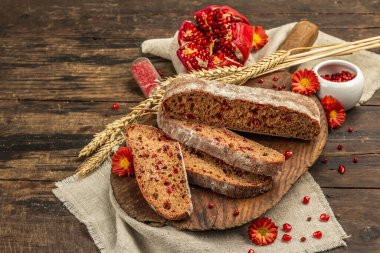 Tatillerde yaban mersinli tam tahıllı ekmek. Taze ev yapımı fırın, olgun nar, kuru dikenler. Sonbahar kasımpatıları, eski ahşap zemin, kopyalama alanı