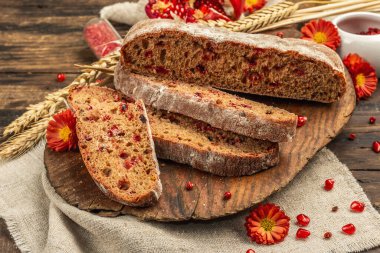 Tatillerde yaban mersinli tam tahıllı ekmek. Taze ev yapımı fırın, olgun nar, kuru dikenler. Sonbahar kasımpatıları, eski ahşap arka plan, yakın plan.