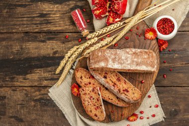 Tatillerde yaban mersinli tam tahıllı ekmek. Taze ev yapımı fırın, olgun nar, kuru dikenler. Sonbahar kasımpatıları, eski ahşap arka plan, üst manzara.