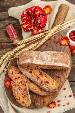 Tatillerde yaban mersinli tam tahıllı ekmek. Taze ev yapımı fırın, olgun nar, kuru dikenler. Sonbahar kasımpatıları, eski ahşap arka plan, üst manzara.