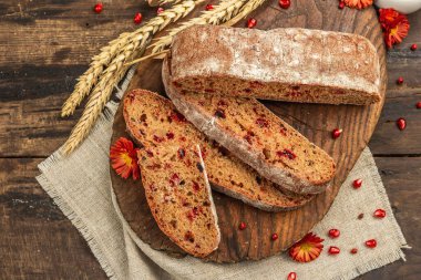 Tatillerde yaban mersinli tam tahıllı ekmek. Taze ev yapımı fırın, olgun nar, kuru dikenler. Sonbahar kasımpatıları, eski ahşap arka plan, üst manzara.