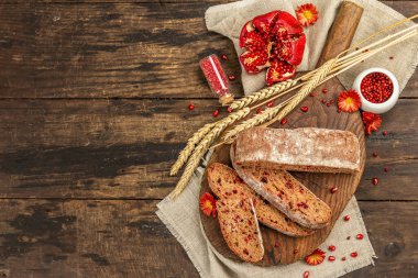 Tatillerde yaban mersinli tam tahıllı ekmek. Taze ev yapımı fırın, olgun nar, kuru dikenler. Sonbahar kasımpatıları, eski ahşap arka plan, üst manzara.