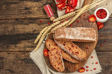 Tatillerde yaban mersinli tam tahıllı ekmek. Taze ev yapımı fırın, olgun nar, kuru dikenler. Sonbahar kasımpatıları, eski ahşap arka plan, üst manzara.