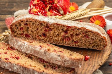Tatillerde yaban mersinli tam tahıllı ekmek. Taze ev yapımı fırın, olgun nar, kuru dikenler. Sonbahar kasımpatıları, eski ahşap arka plan, yakın plan.