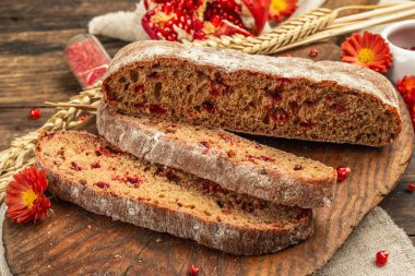 Tatillerde yaban mersinli tam tahıllı ekmek. Taze ev yapımı fırın, olgun nar, kuru dikenler. Sonbahar kasımpatıları, eski ahşap arka plan, yakın plan.