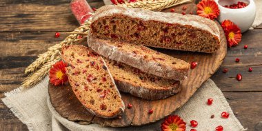 Tatillerde yaban mersinli tam tahıllı ekmek. Taze ev yapımı fırın, olgun nar, kuru dikenler. Sonbahar kasımpatıları, eski ahşap zemin, afiş biçimi