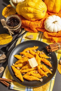 Tembel balkabaklı börek, tereyağlı gnocchi ve esmer şeker. Sıcak sonbahar yemeği, tatlı ve sağlıklı yemek. Siyah taş beton zemin, modaya uygun sert ışık, karanlık gölge, üst görüş