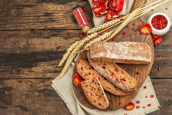 Tatillerde yaban mersinli tam tahıllı ekmek. Taze ev yapımı fırın, olgun nar, kuru dikenler. Sonbahar kasımpatıları, eski ahşap arka plan, üst manzara.