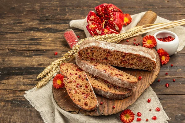 Tatillerde yaban mersinli tam tahıllı ekmek. Taze ev yapımı fırın, olgun nar, kuru dikenler. Sonbahar kasımpatıları, eski ahşap arka plan, yakın plan.